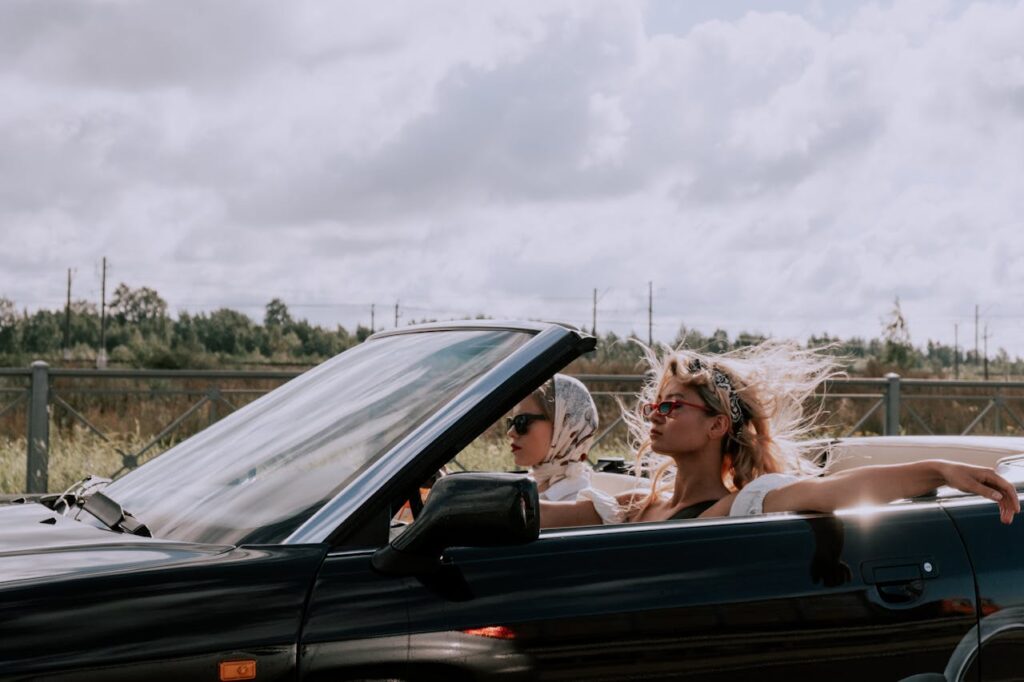 Two fashionable women driving a convertible with sunglasses, capturing the essence of freedom and style.